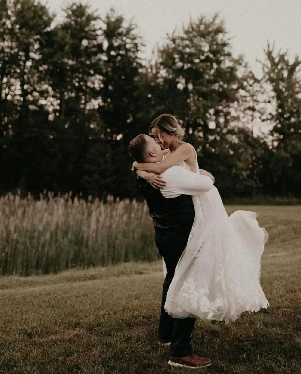 bride and groom kissing in field
